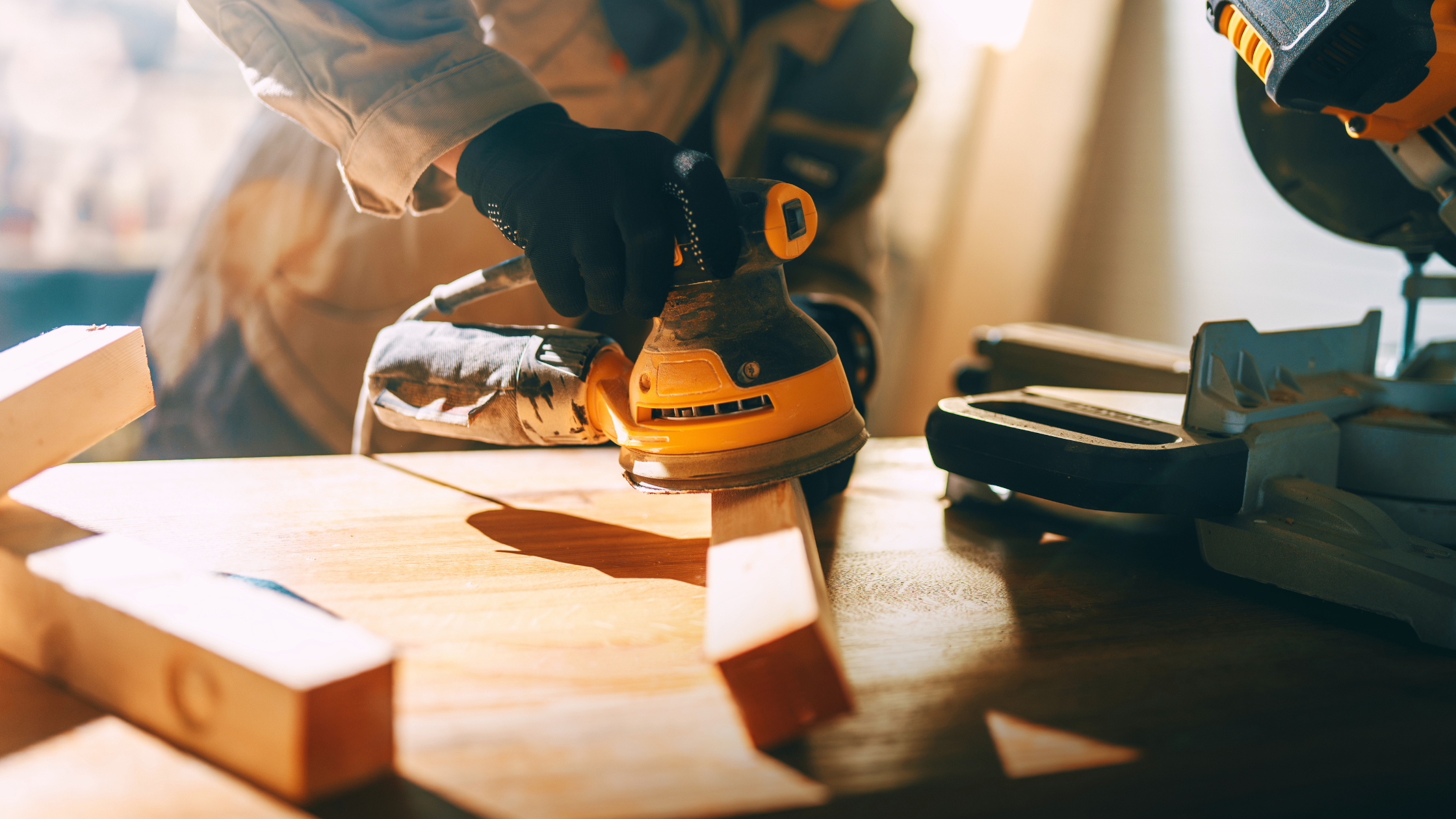 Carpenter using a power sander to smooth a piece of wood in a workshop