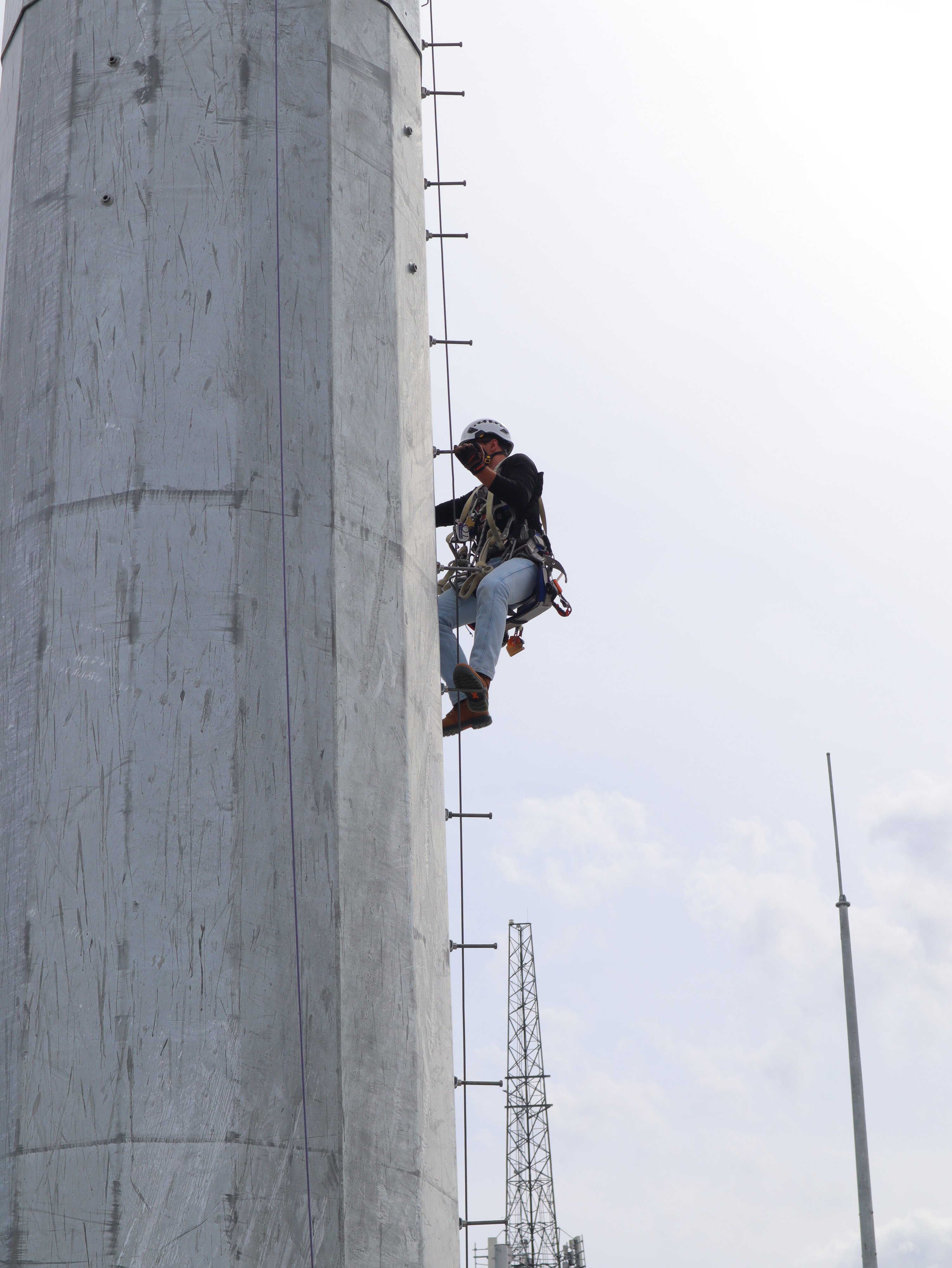 Pinnacle Career Institute student climbing up a monopole tower during hands-on tower technician training, practicing ascent techniques and safety procedures as part of PCI’s Telecommunications Tower Technician program.