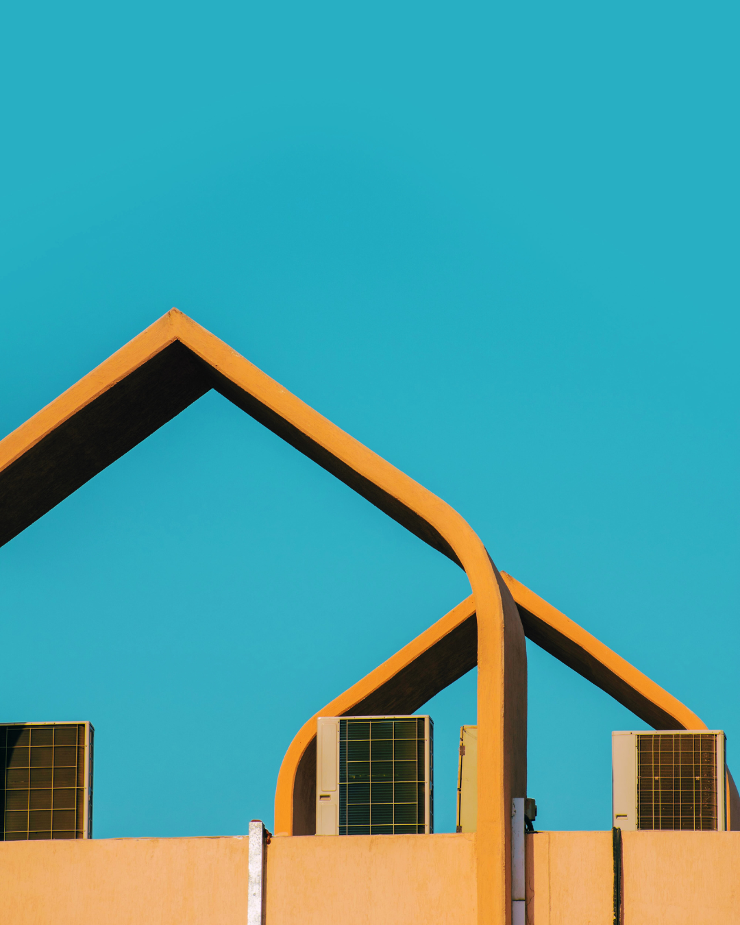 Row of rooftop air conditioning systems framed against a bright sky.