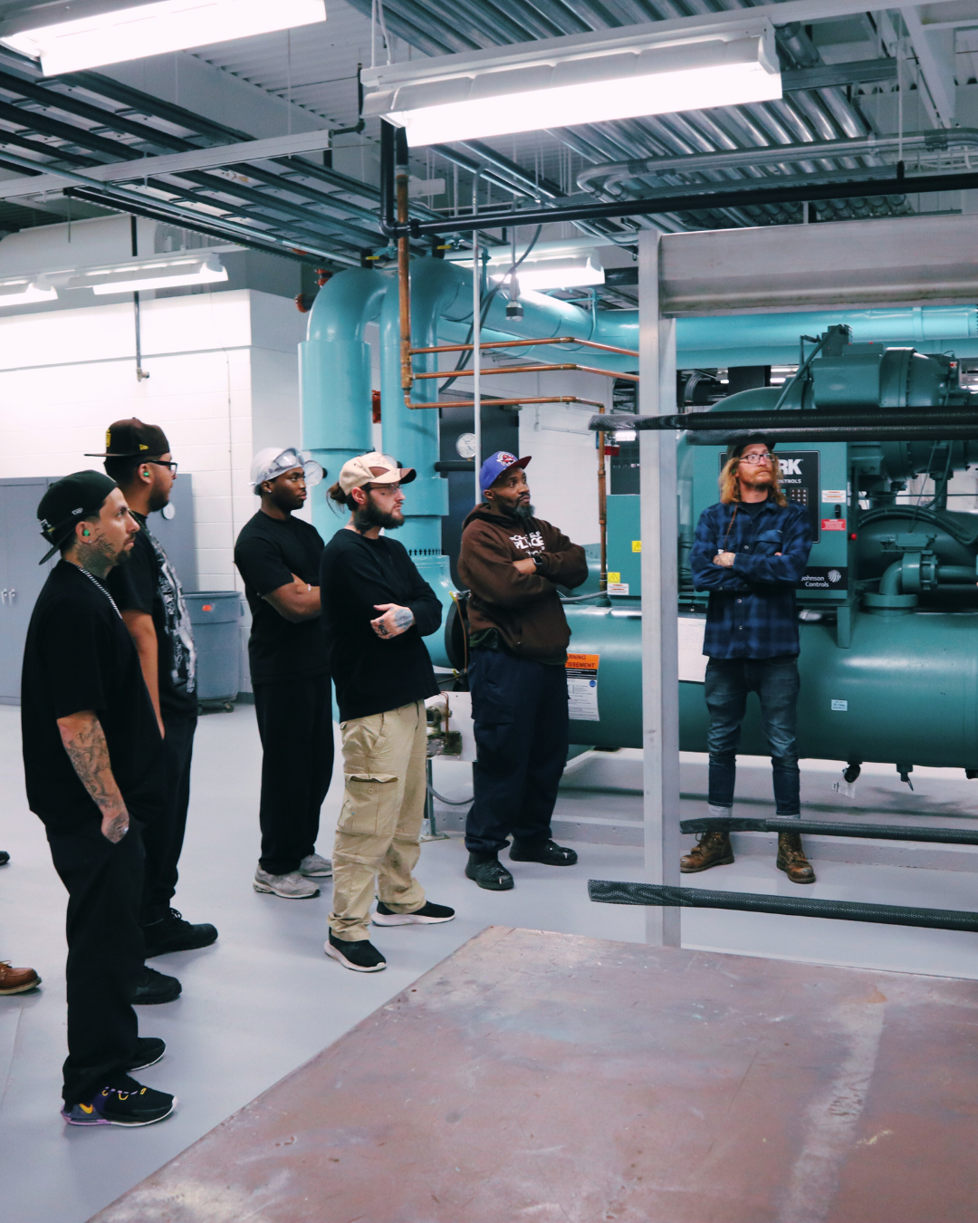 Group of HVAC students and instructor gathered around large industrial equipment during training.