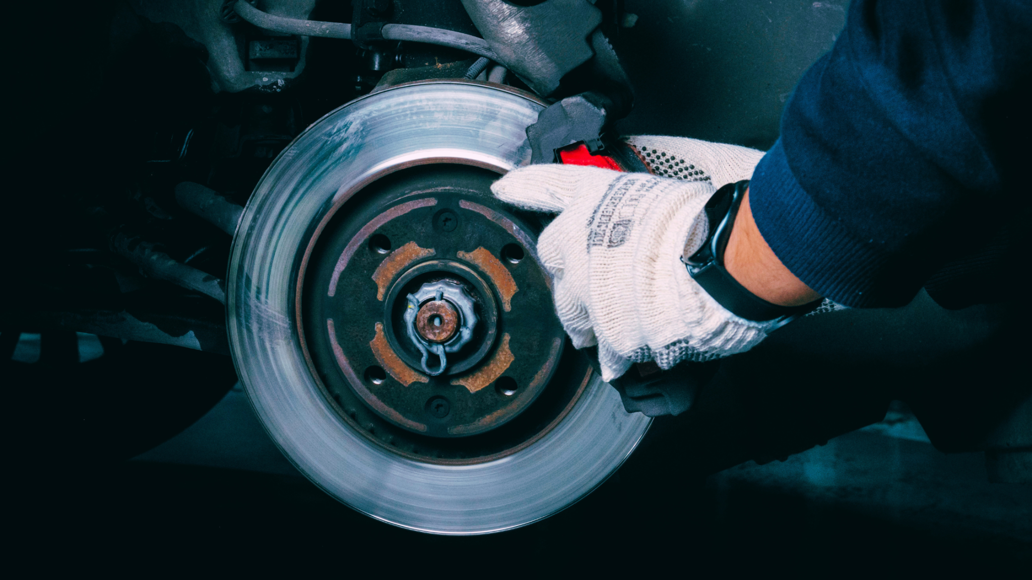 Automotive service technician inspecting a vehicle’s brake rotor and brake assembly