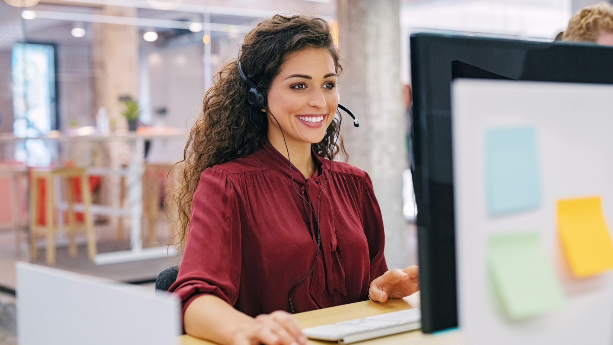 Woman wearing a headset while working at a desktop computer.