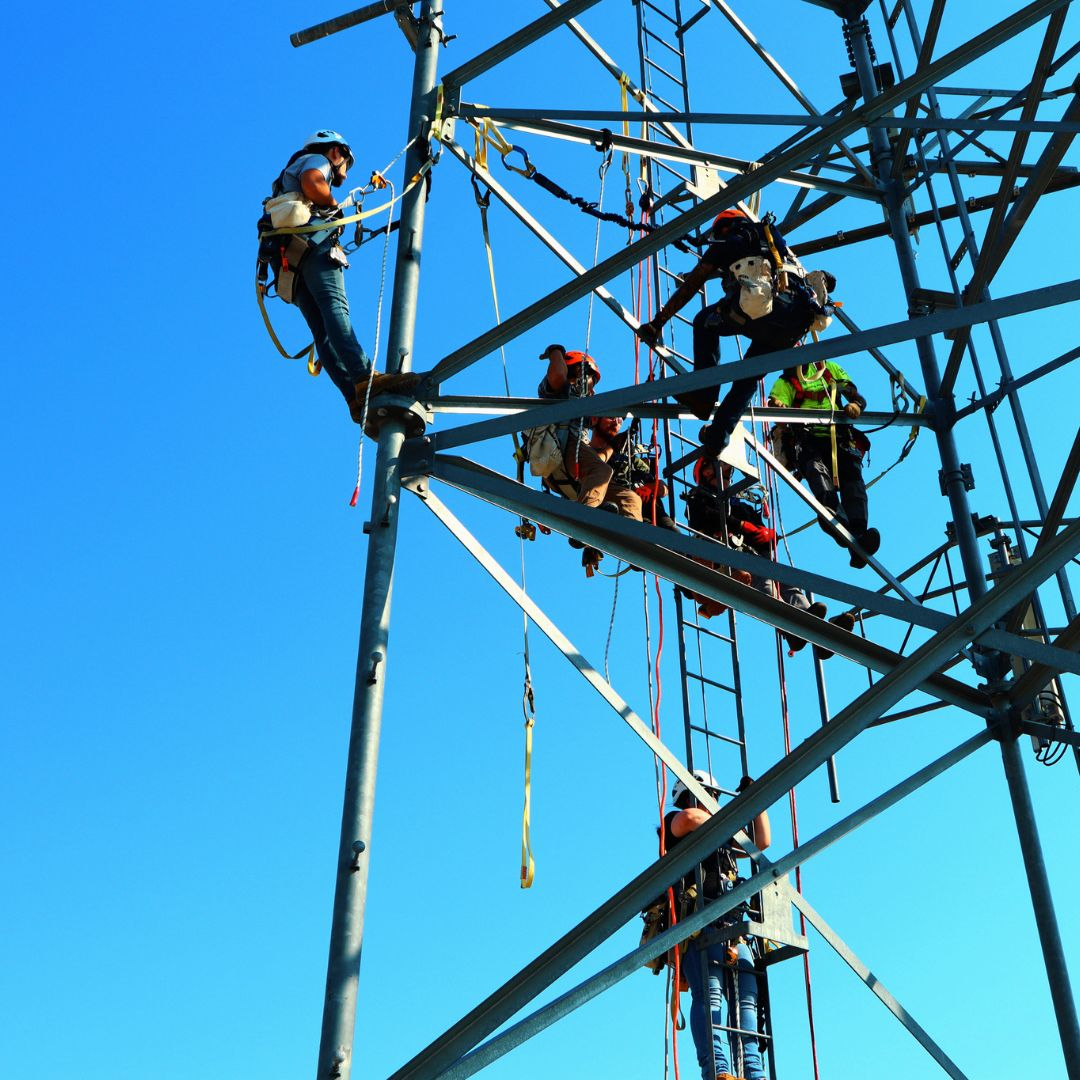 Hands-on tower technician training at Pinnacle Career Institute, with students climbing steel structures under instructor supervision.