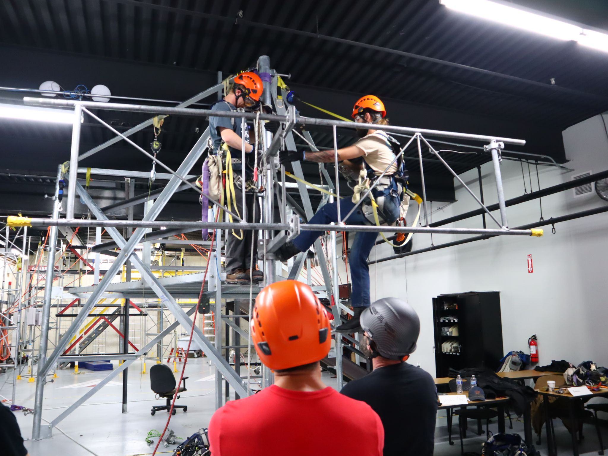 Tower technician trainees practicing safe rigging and equipment handling during indoor training at Pinnacle Career Institute.