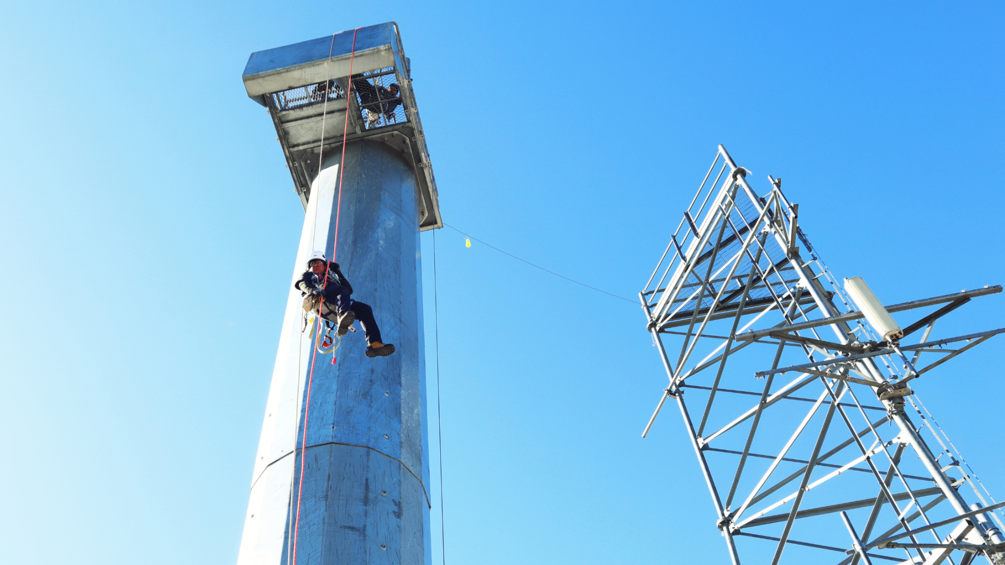 Tower technician descending a monopole during hands-on tower climbing training